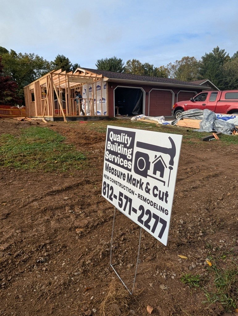 Quality Building Services yard sign on an active construction site